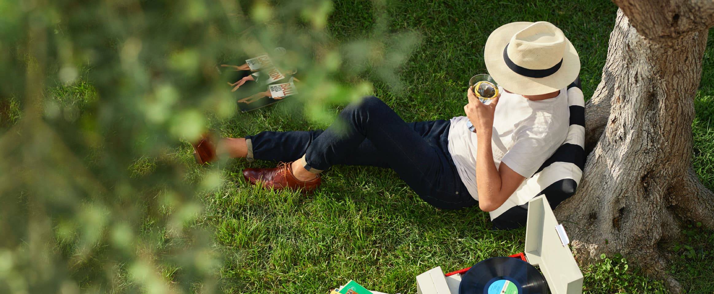 person sitting under a tree drinking a cocktail